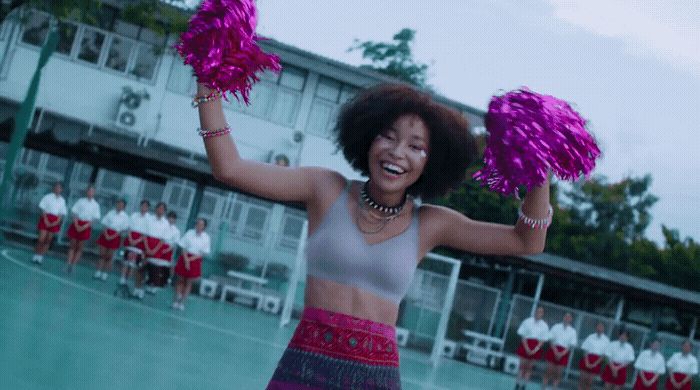 a woman in a skirt holding two pink pom poms