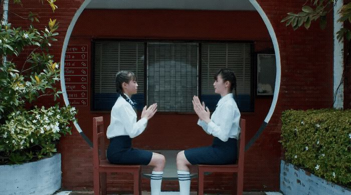 two women sitting on chairs in front of a building