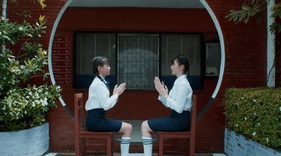 two women sitting on chairs in front of a building