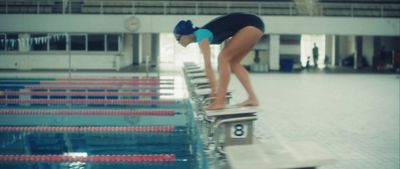 a woman standing on a diving board in a swimming pool