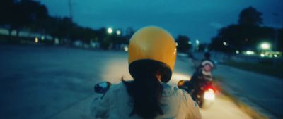 a woman riding a motorcycle down a street at night