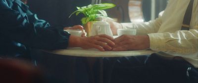 two people sitting at a table holding hands