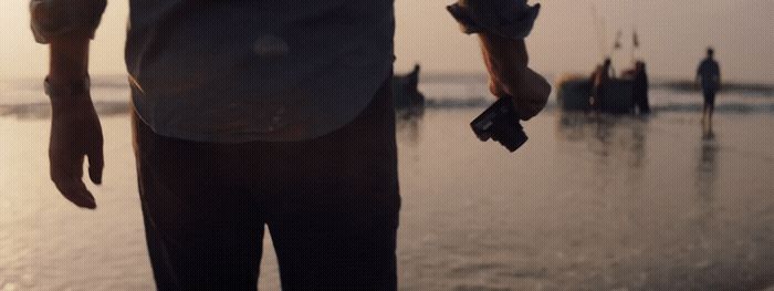 a man standing on a beach holding a cell phone