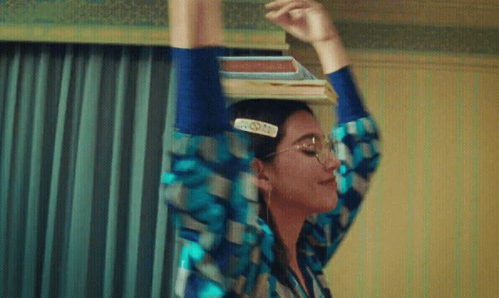 a woman holding a stack of books above her head