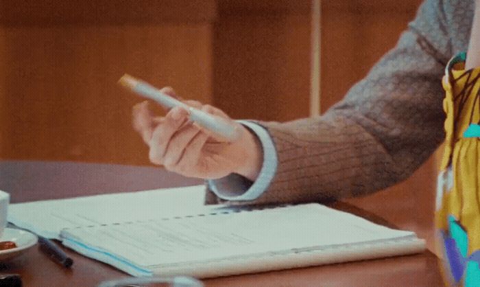 a person sitting at a table with a pen in their hand