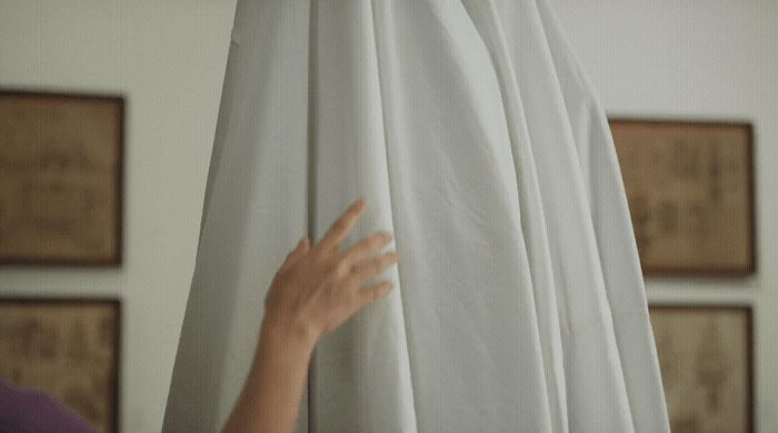 a woman is hiding behind a white curtain