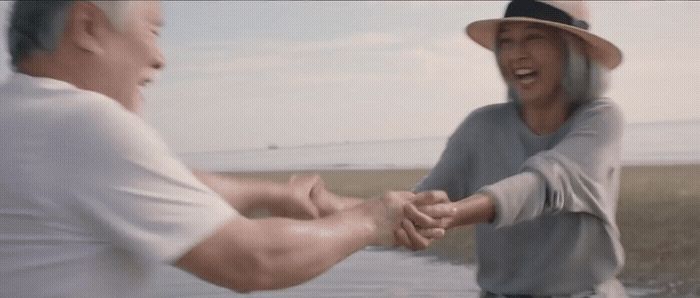 a man and a woman holding hands near a body of water