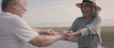 a man and a woman holding hands near a body of water