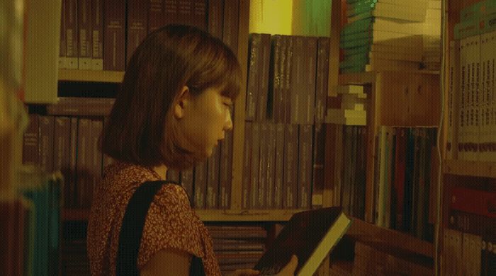 a woman is reading a book in a library