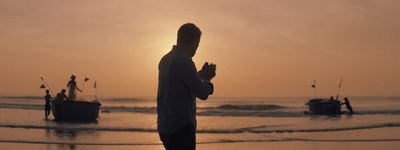 a man standing on a beach next to a boat