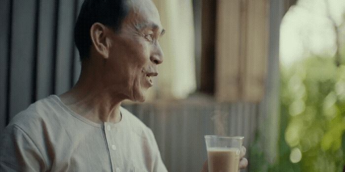 an old man holding a glass of milk