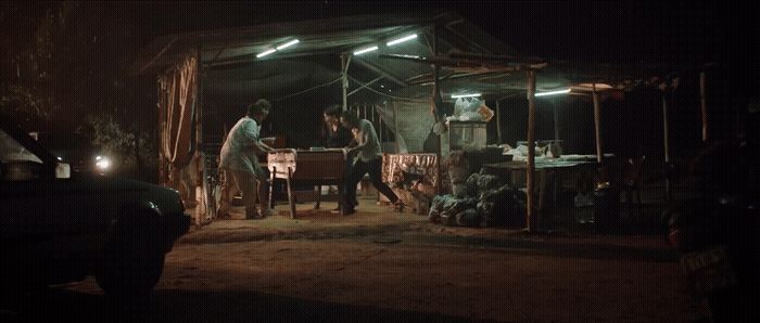 a group of people standing outside of a tent at night