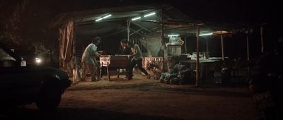 a group of people standing outside of a tent at night