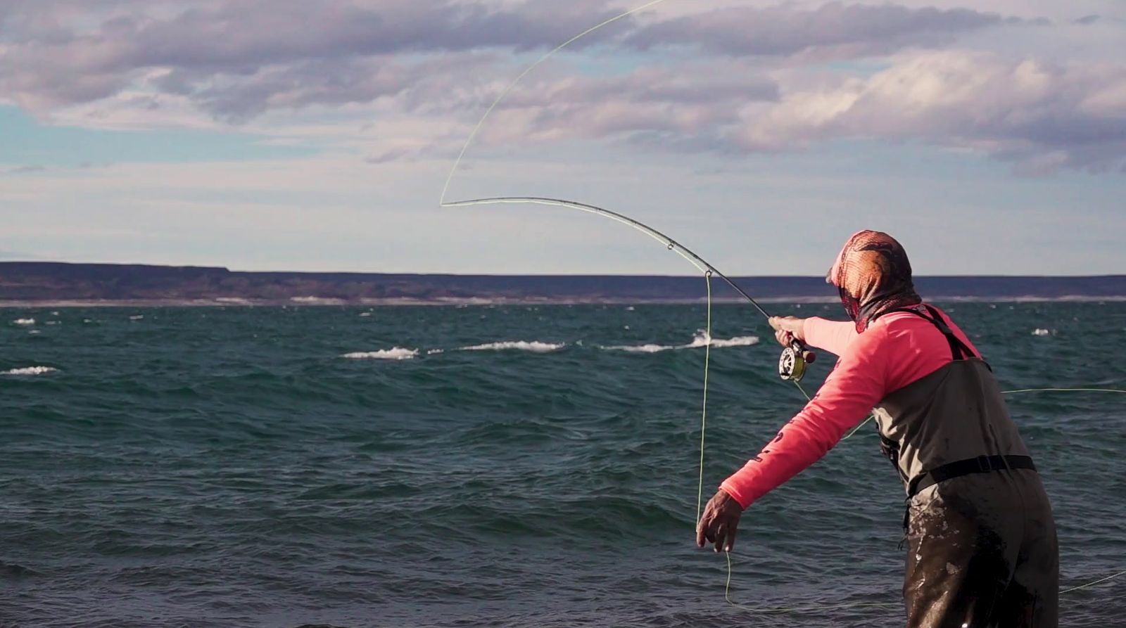 a man standing on top of a beach holding a fishing pole