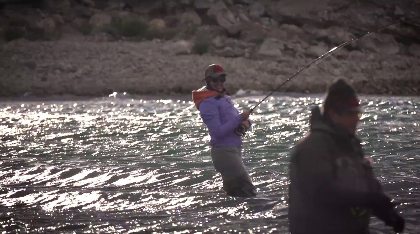 a man standing in the water while holding a fishing rod