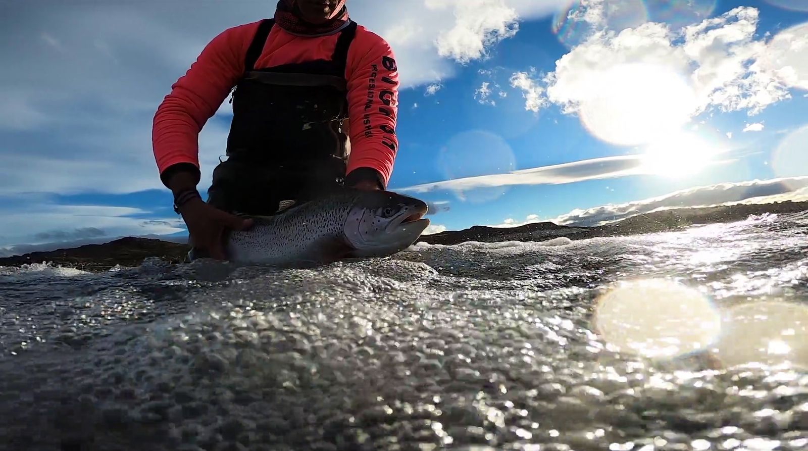 a man standing in the water holding a fish