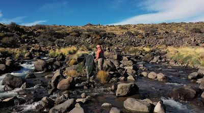 a man standing on rocks next to a river