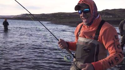 a man holding a fishing rod while standing in the water