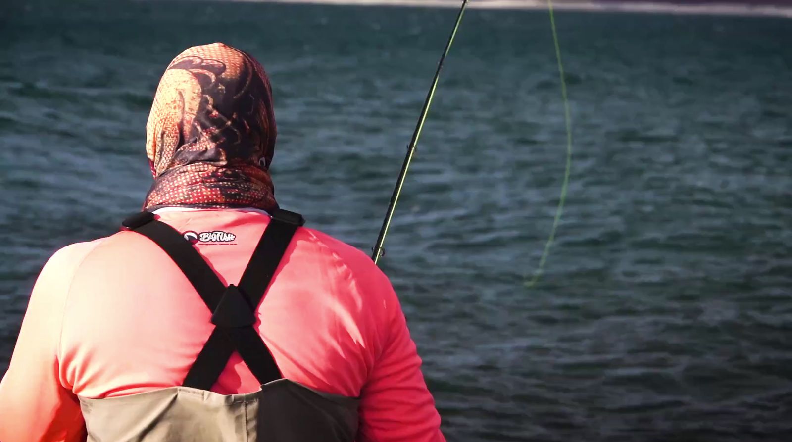 a man in a pink shirt fishing on a lake