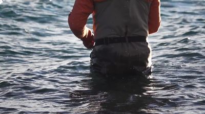 a man standing in the water wearing a life jacket