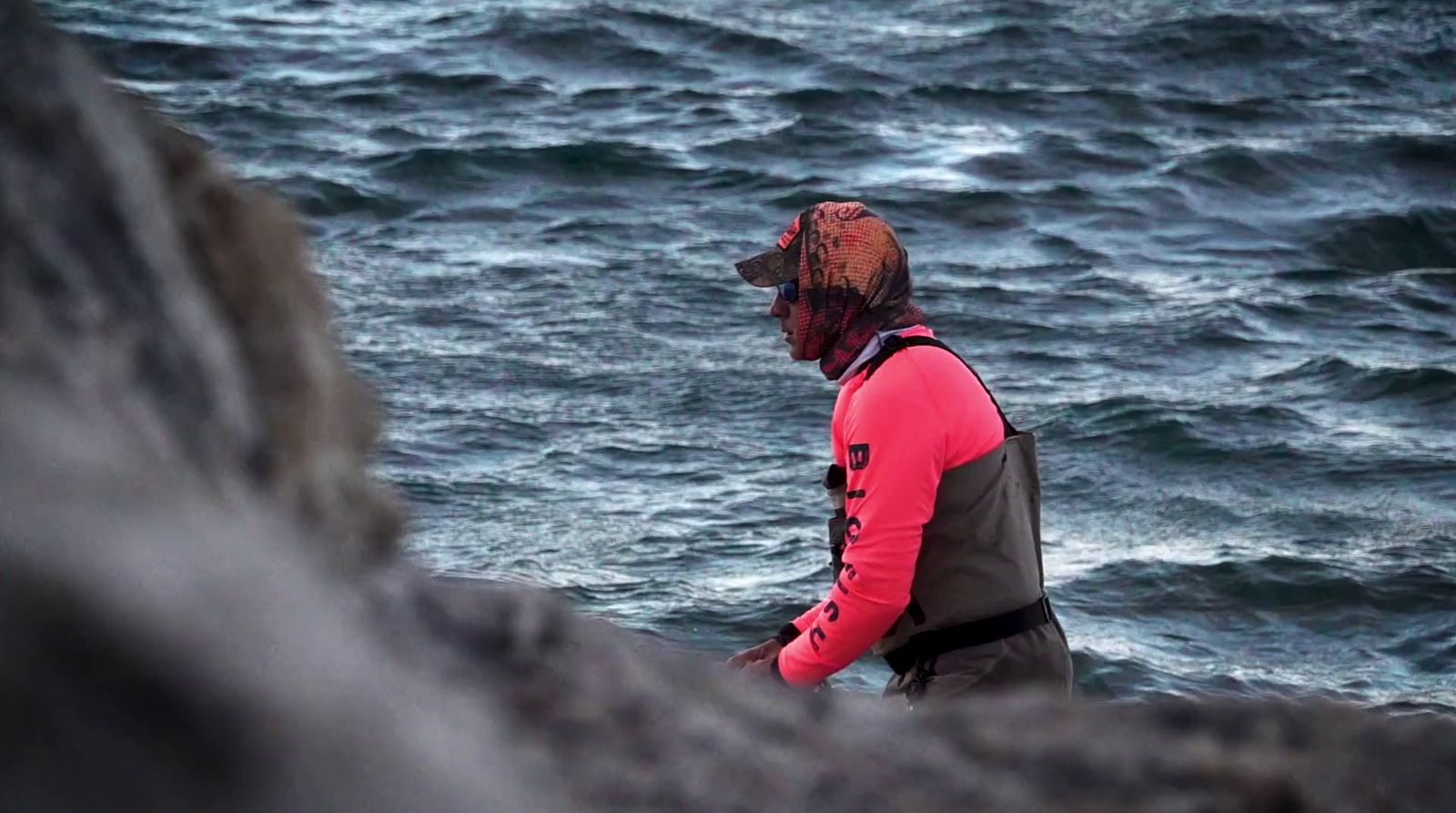 a man standing on top of a rocky cliff next to the ocean