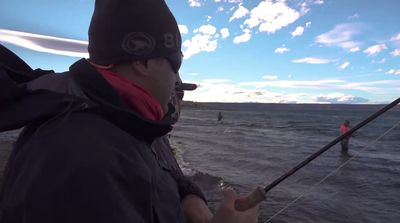 a man holding a fishing rod while standing on a boat