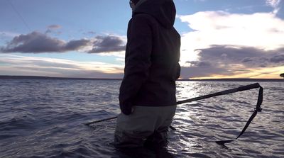 a man standing in the water holding a fishing pole