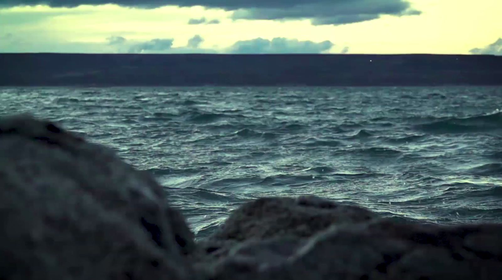 a body of water sitting next to a rocky shore