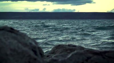 a body of water sitting next to a rocky shore