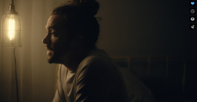 a man sitting in a dark room next to a lamp