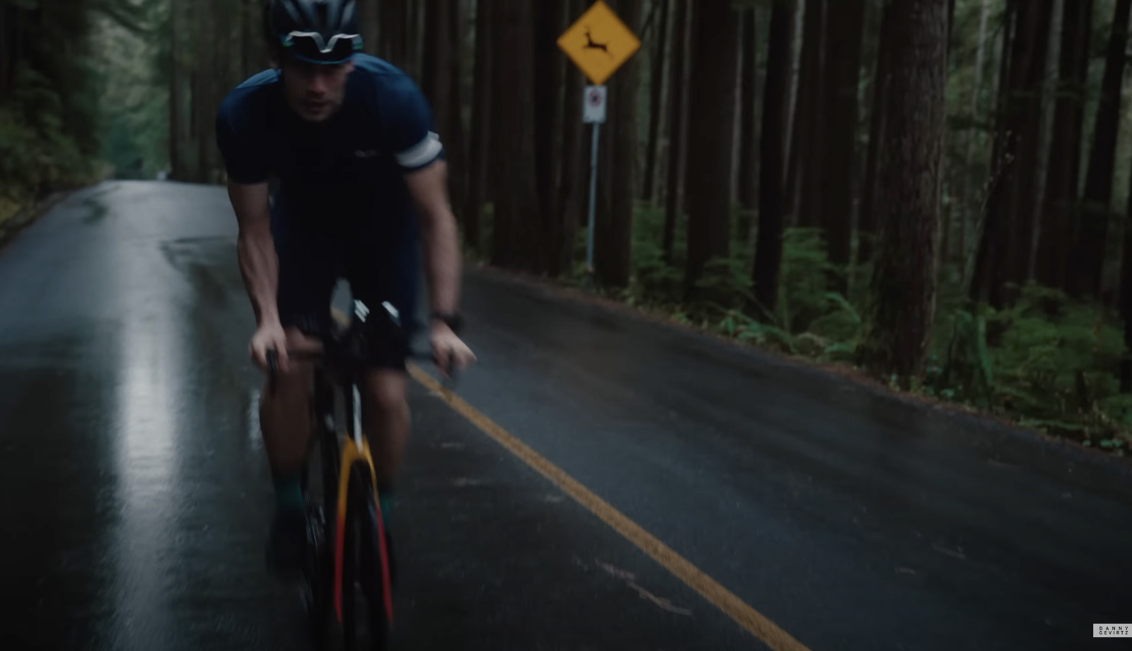 a man riding a bike down a wet road