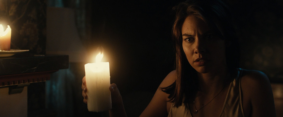 a woman holding a lit candle in a dark room