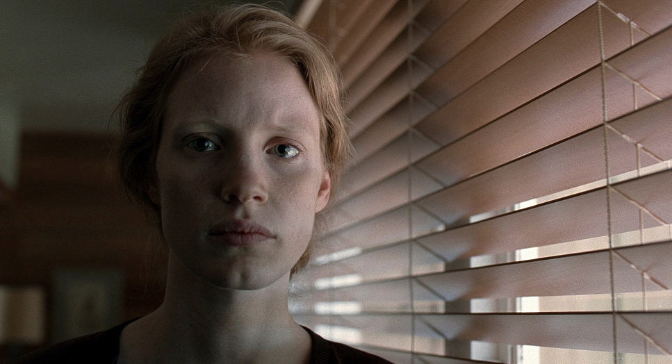 a woman standing in front of a window covered in blinds