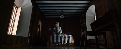 a woman standing in a dark room with a suitcase