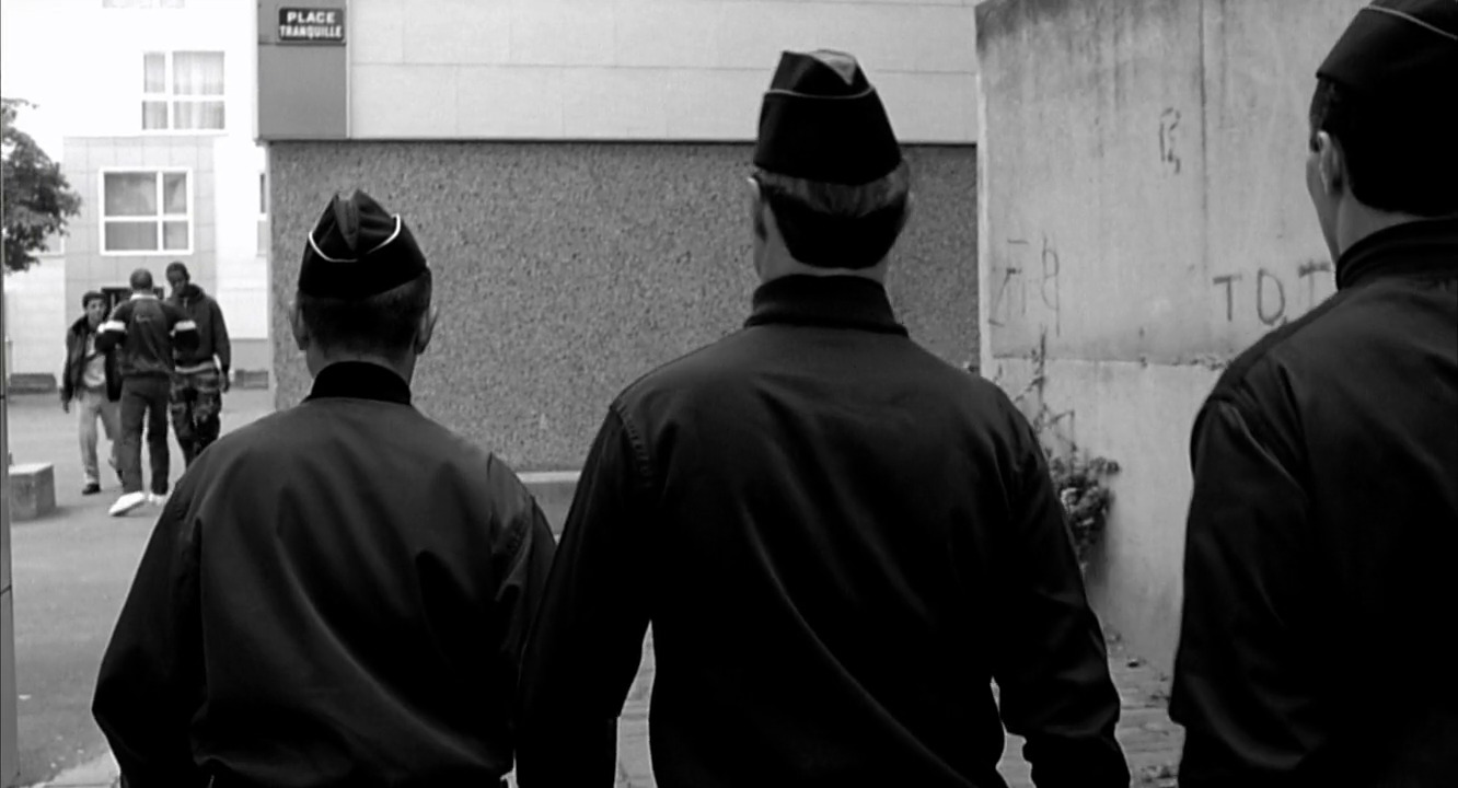 a group of men walking down a street next to a tall building