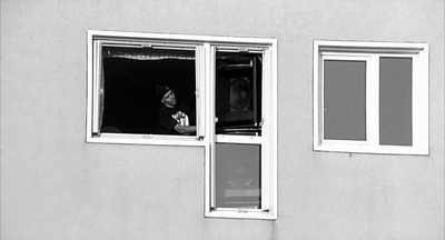 a black and white photo of a person looking out a window