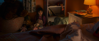 a little girl sitting on a bed with stuffed animals