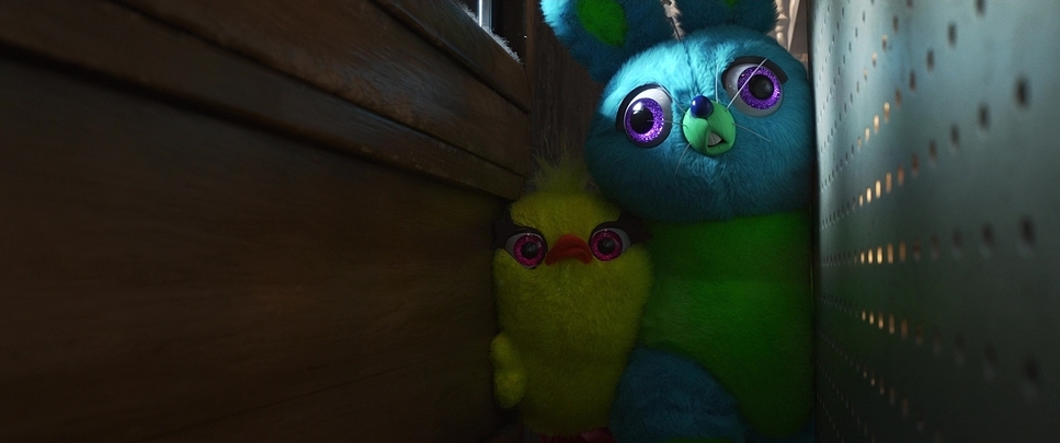 a blue and green stuffed animal next to a wooden wall