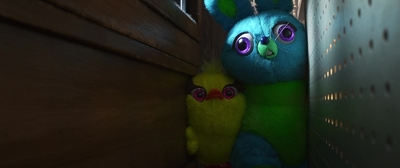 a blue and green stuffed animal next to a wooden wall