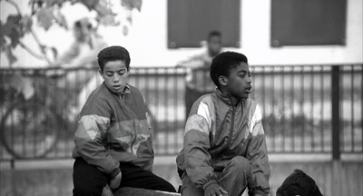 two boys sitting on a bench with a dog