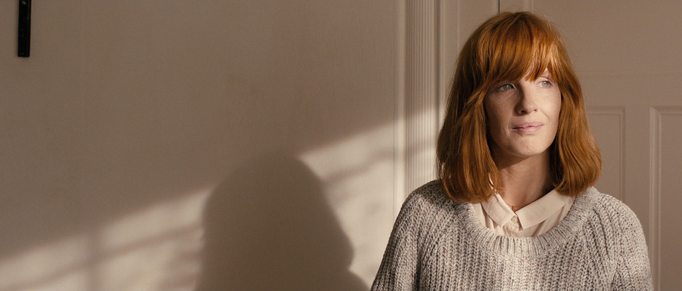 a woman with red hair standing in front of a door