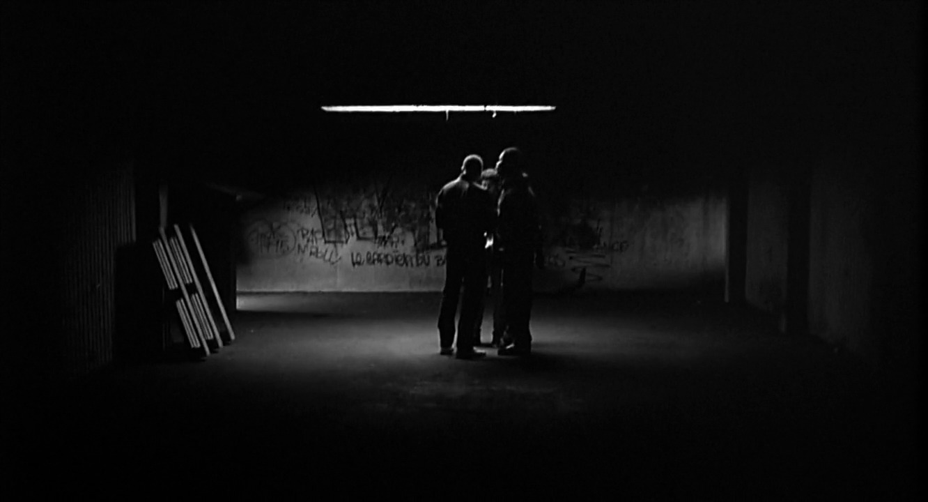 a couple of men standing in a dark room