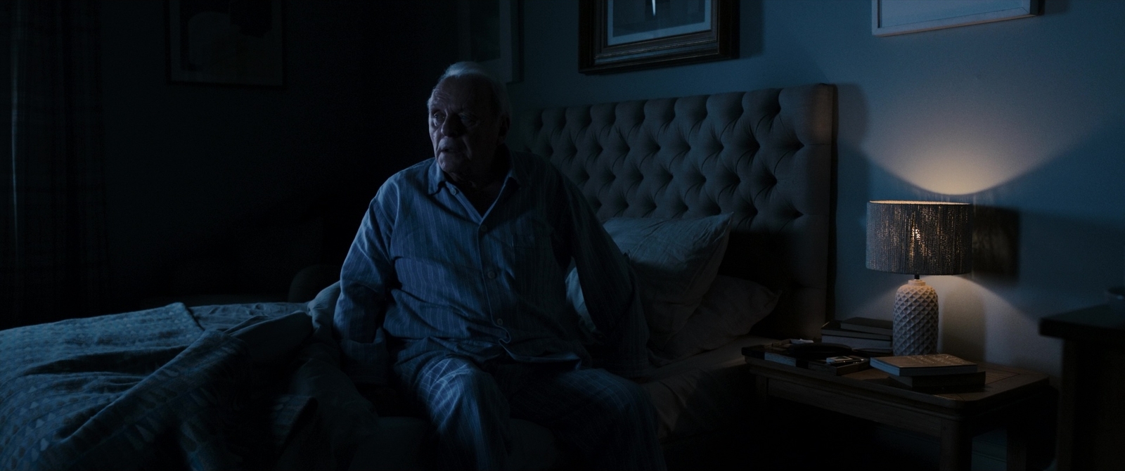 a man sitting on a bed in a dark room