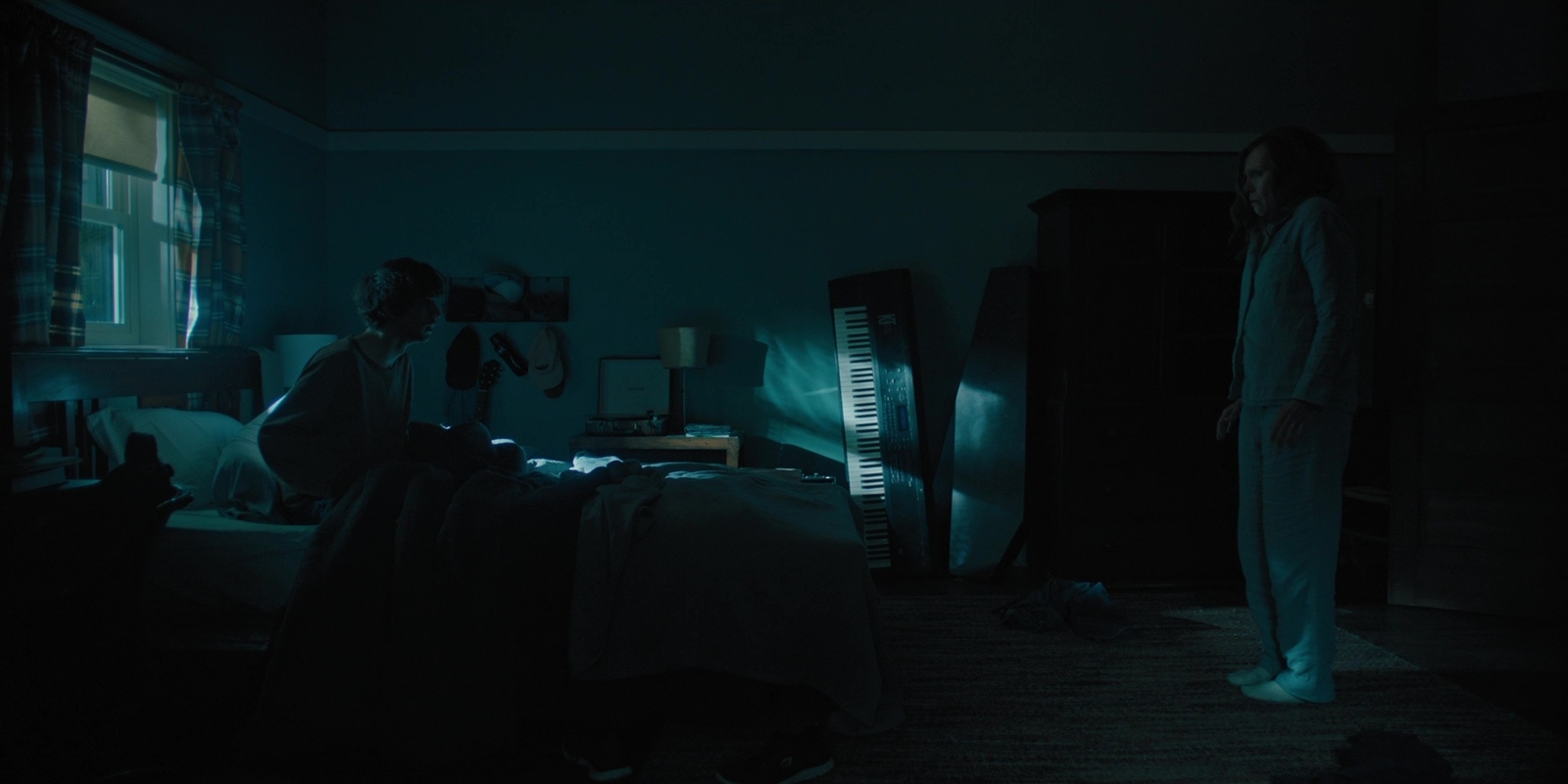 a woman standing in a dark room next to a piano