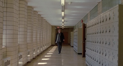 a man walking down a hallway between rows of lockers