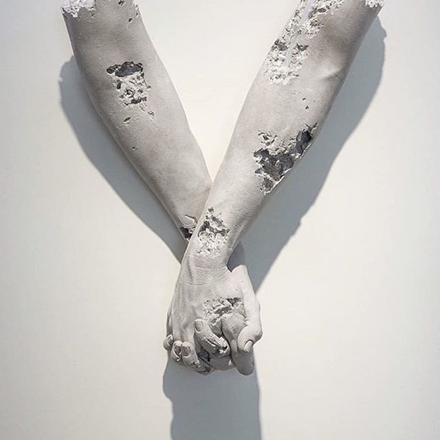 a pair of hands holding each other on a white surface