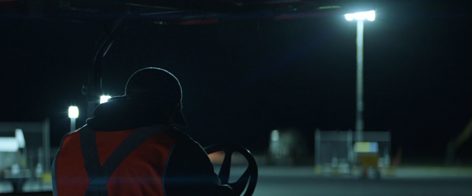 a person wearing a safety vest standing in a parking lot at night