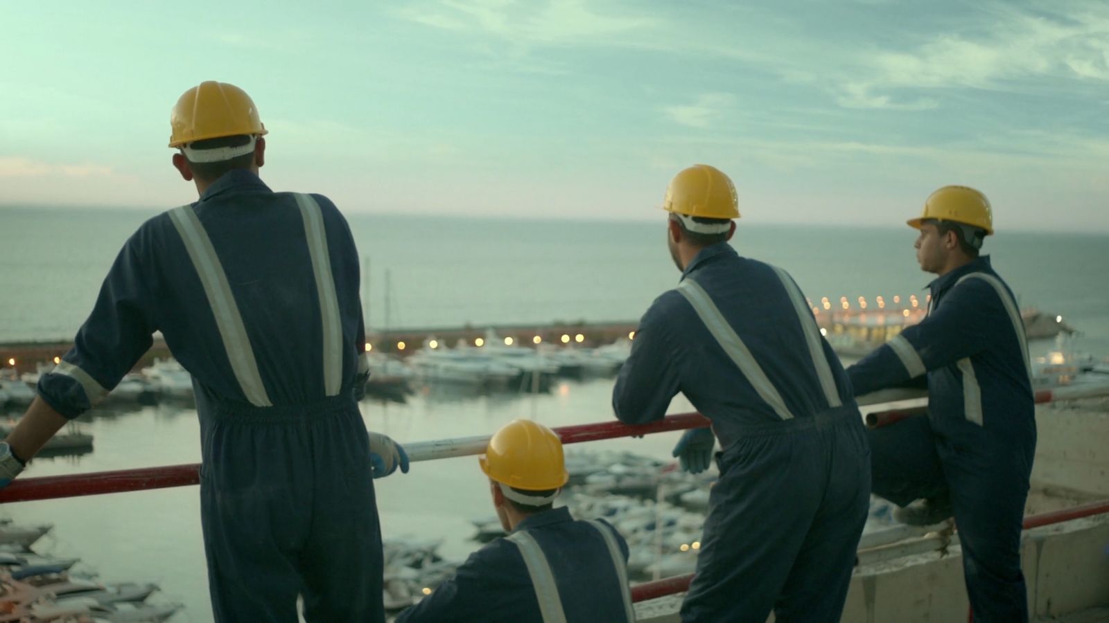 a group of men standing next to each other near a harbor