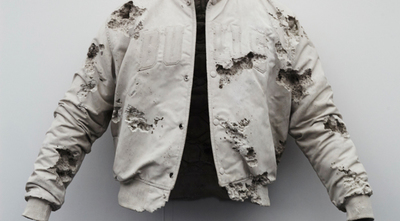 a white jacket with holes on it hanging on a wall