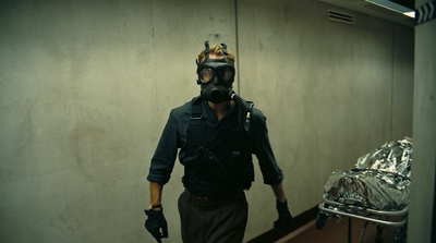 a man in a gas mask walks down a hallway